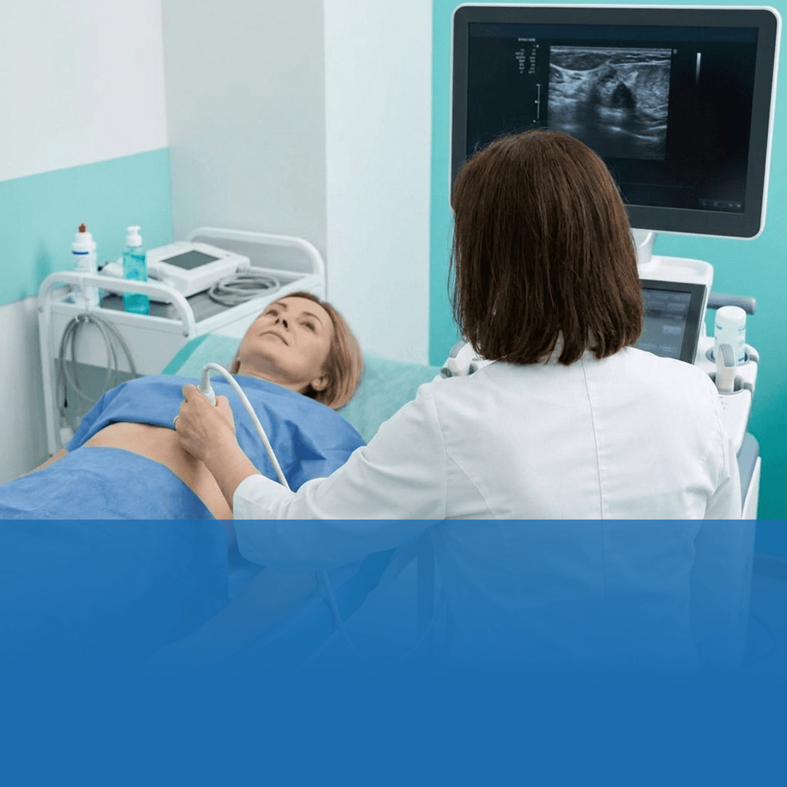 Medical professional performs an abdominal ultrasound on a patient lying on an exam bed, monitor displaying ultrasound images.